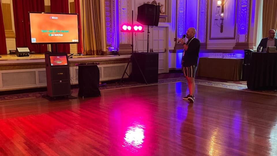 A hosted karaoke setup in a Vancouver ballroom, lyrics on the screen and the host working the floor
