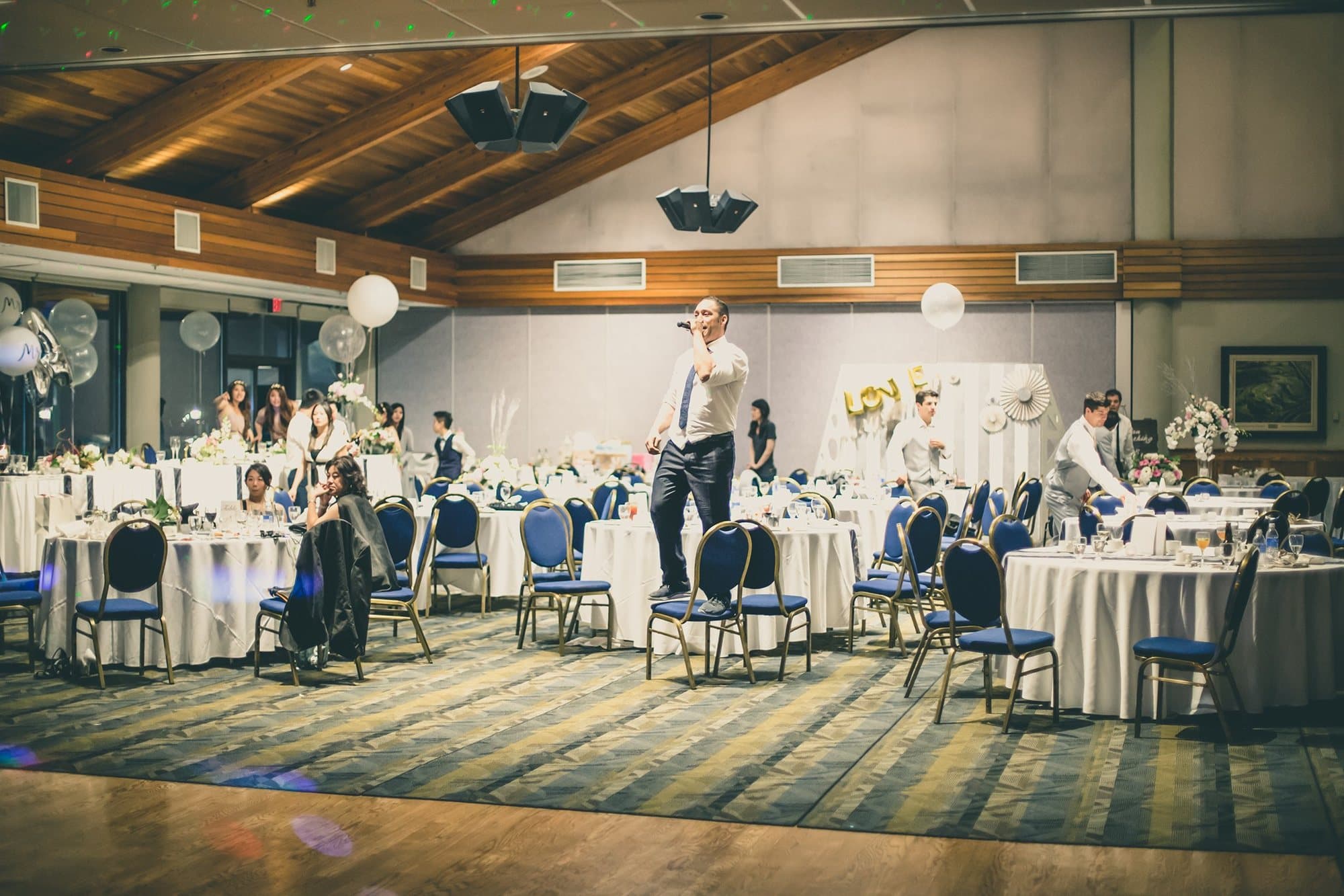 Vancouver MC on the microphone in a ballroom before the floor fills