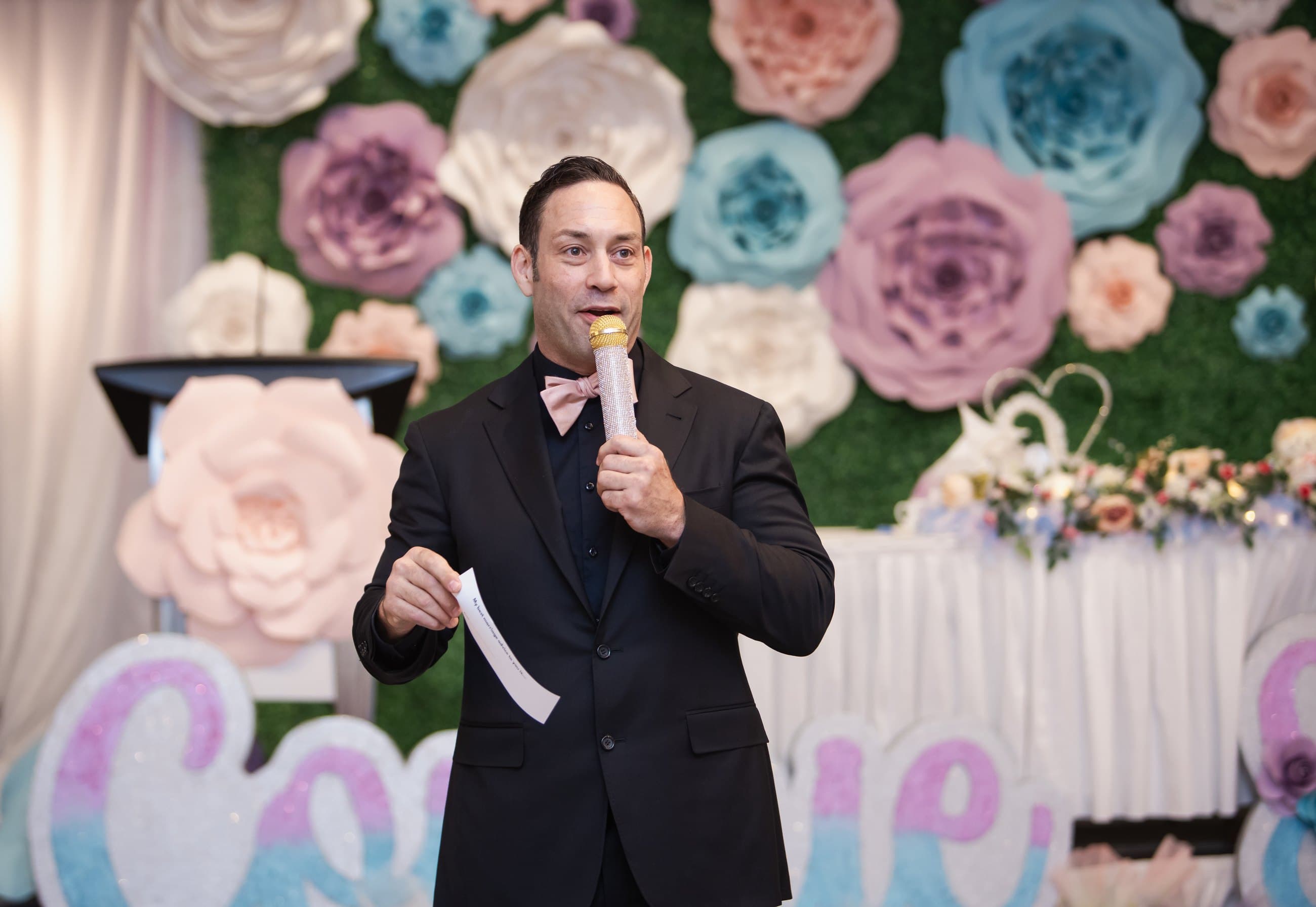 Mike Oulton hosting in front of a floral wedding backdrop